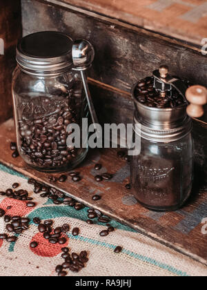 Stile vecchio macinino da caffè e caffè in grani in vasetti di vetro Foto Stock