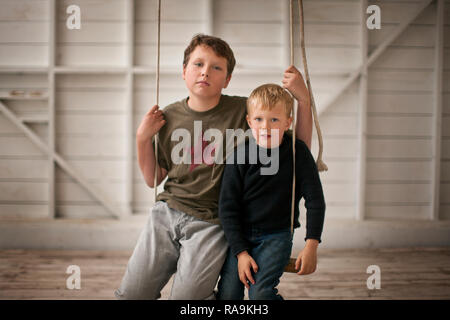 Ritratto di due giovani ragazzi seduti su un altalena. Foto Stock