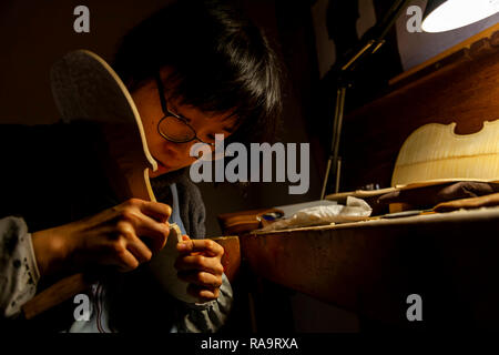 Femmina artigiano liutaio lavorando su un nuovo violino in officina Foto Stock