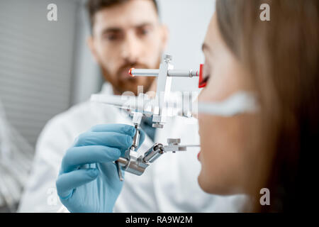 Dentista ganascia mettendo il sistema di misura a una giovane donna paziente nello studio dentistico, vista da vicino Foto Stock