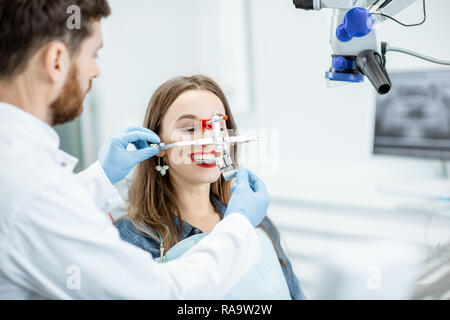 Dentista ganascia mettendo il sistema di misura a una giovane donna paziente nello studio dentistico Foto Stock