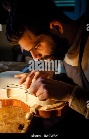 Maschio artigiano liutaio lavorando su un nuovo violino in officina Foto Stock