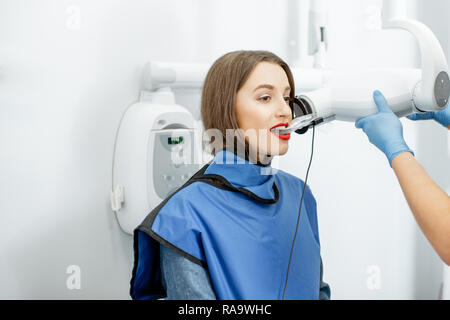 Giovane donna in abbigliamento protettivo rendendo x--ray colpo di un dente in studio dentistico Foto Stock