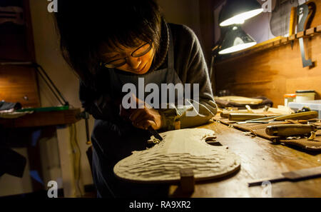 Femmina artigiano liutaio lavorando su un nuovo violino in officina Foto Stock