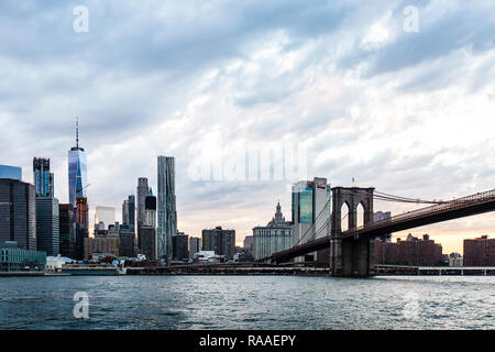 La skyline di Manhattan e Brooklyn Bridge al tramonto visto attraverso l'East River da Brooklyn Heights Esplanade, New York City, NY, STATI UNITI D'AMERICA Foto Stock