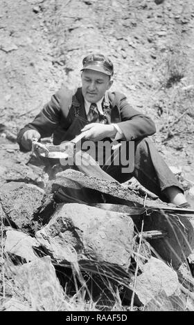 Un uomo cuochi in collina falò in Colorado, ca. 1928. Foto Stock