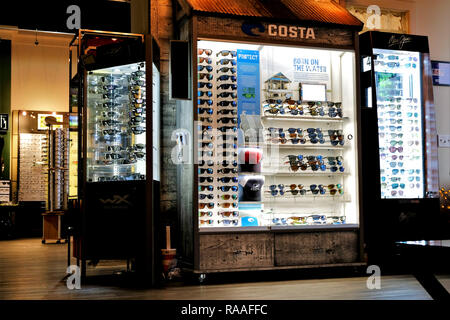 Display illuminato caso per Costa e Maui Jim occhiali da sole; all'ottico optometrista negozio interno. Foto Stock