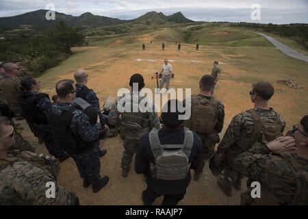 Gli studenti osservano come il loro maestro li presenta con il Mossberg 12 Gage fucile durante l'armi Non-Lethal corso istruttori su Camp Hansen, Okinawa, in Giappone. Marines, marinai, aviatori e giapponese guardie di sicurezza completa una settimana lungo armi Non-Lethal Instructor, che copriva la Malga Taser formazione, OC esposizione e antisommossa le tattiche di squadra. Foto Stock