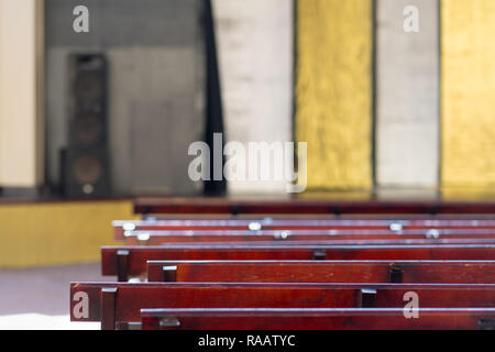 Righe vuote di panche di legno o banchi visto elevato angolo contro decorativo in oro e argento sfondo Foto Stock