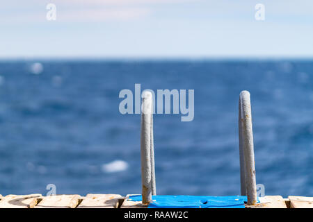 Acciaio inossidabile passaggi su una tavola di legno pontile o molo che si affaccia su un tranquillo blu oceano concettuale del vacanze estive o sport Foto Stock