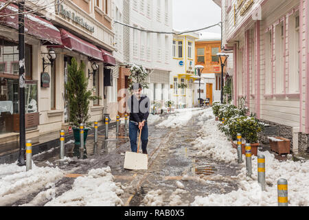 Istanbul, Turchia, febbraio 19, 2015: Turco uomo cancellazione sonow al di fuori di un ristorante nel quartiere di Eyup. Foto Stock