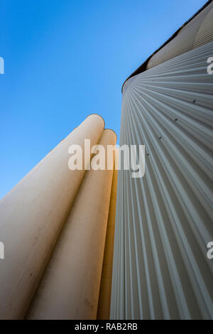 Industrial silos per il grano contro un cielo blu, forte prospettiva verso l'alto Foto Stock