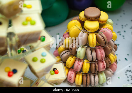 Mousse in bicchieri e colorati macarons francese torta multilivello piramide sul dessert in plastica stand. colorati macarons francesi disposti sulla piramide Foto Stock