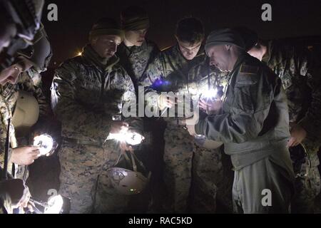 1Lt. John Adams, destra, 36th Airlift Squadron C-130 Hercules navigator, mostra Marines dal 3° Battaglione di ricognizione, terza divisione Marine, III Marine forza expeditionary come operare nella zona di caduta le spie a Yokota Air Base, Giappone, 11 gennaio 2017, durante la settimana di salto. III MEF Marines condotta giro jump training da un U.S. Air Force C-130H, assegnato al 36 COME. La formazione non sono ammessi solo i Marines a praticare il salto, ma ha anche permesso la Yokota personale di volo in pratica tattiche di volo e il tempo-package scende. Foto Stock