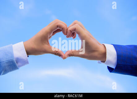 Amore il concetto di simbolo. Lato cuore gesto forme forma utilizzando le dita. Le mani di mettere assieme in forma di cuore cielo blu sullo sfondo. Mani maschio a forma di cuore simbolo del gesto di amore e romanticismo. Foto Stock