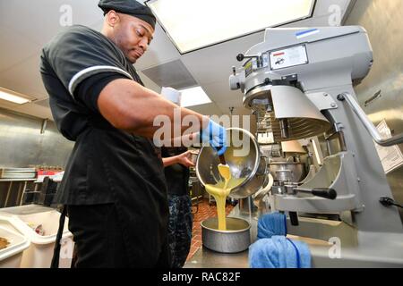 SILVERDALE, nello Stato di Washington (Gen. 18, 2017) specialista culinaria 2a classe Kevin Miller, da Alberta, Georgia, versa l'impasto in preparazione per il Tridente Inn Galley di Martin Luther King Jr. pasto al giorno. Il MLK pasto è un evento annuale in memoria di Martin Luther King Jr. e dei suoi successi durante i diritti civili Era. Foto Stock