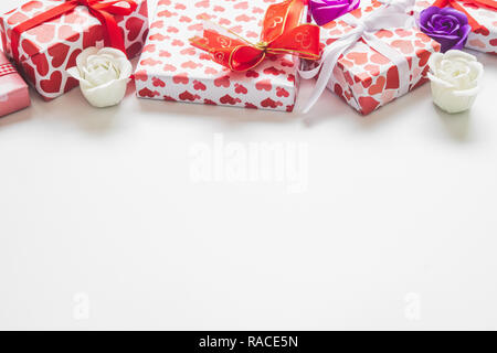 Il giorno di San Valentino sfondo con confezioni regalo con cuori forma involucro di carta e le rose su sfondo bianco. Foto Stock
