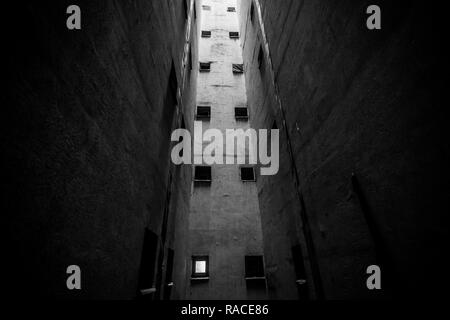 Piccolo bagno windows in un aeratore pit all interno di un alto era comunista blocco di appartamenti a Bucarest, Romania (bianco e nero). Foto Stock