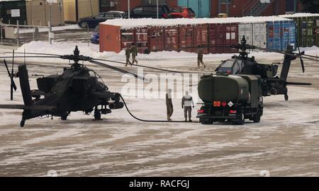 In un freddo e ventoso pomeriggio, soldati del primo battaglione, 3° Reggimento di aviazione (attacco ricognizione), xii combattere la Brigata Aerea, di fare rifornimento di carburante un AH-64 elicottero Apache gen. 18, 2017 a Katterbach Army Airfield in Ansbach, Baviera, Germania. Foto Stock