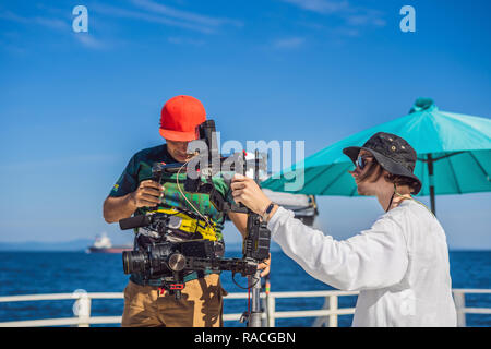 Steadicam operatore e il suo assistente Preparazione della fotocamera e 3-asse-stabilizzatore di sospensione cardanica per un commerciale shoot Foto Stock