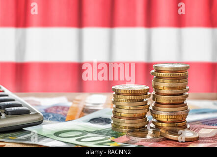 Le banconote e le monete in euro di fronte alla bandiera nazionale dell'Austria Foto Stock