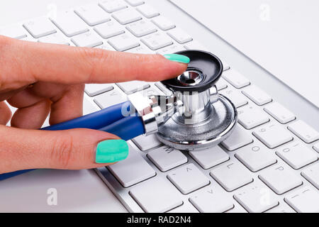 Il tecnico femmina (donna) mano utilizzando uno stetoscopio per esamina la tastiera del computer, computer service concetto, computer e internet manutenzione, controllo Foto Stock