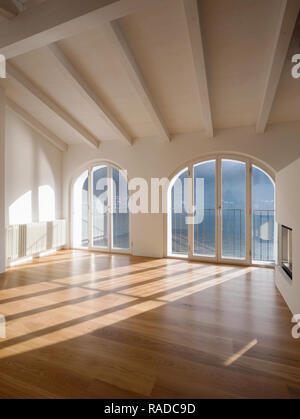 Stanza vuota con una grande finestra che si affaccia sul lago. Le antiche travi sul soffitto di un appartamento ristrutturato Foto Stock