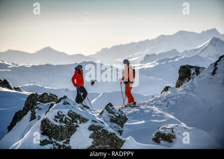 Due gli sciatori stand su una cresta sopra Courchevel guardando fuori attraverso le tre valli ski area nelle Alpi francesi. Foto Stock