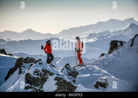 Due gli sciatori stand su una cresta sopra Courchevel guardando fuori attraverso le tre valli ski area nelle Alpi francesi. Foto Stock