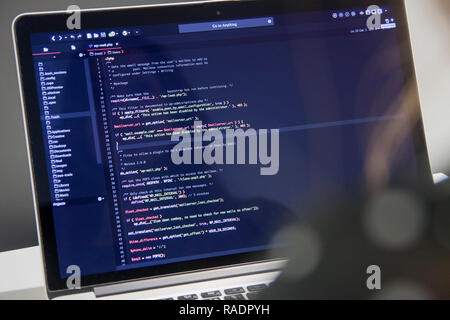 Programmatore di donna con la tazza di caffè lavorando sul computer portatile in codice php in ufficio Foto Stock