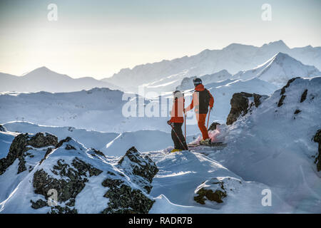 Due gli sciatori stand su una cresta sopra Courchevel guardando fuori attraverso le tre valli ski area nelle Alpi francesi. Foto Stock