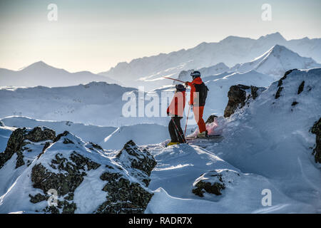 Due gli sciatori stand su una cresta sopra Courchevel guardando fuori attraverso le tre valli ski area nelle Alpi francesi. Foto Stock