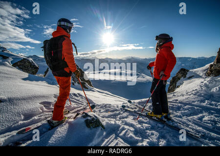 Due gli sciatori stand su una cresta sopra Courchevel guardando fuori attraverso le tre valli ski area nelle Alpi francesi. Foto Stock