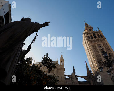 La famosa cattedrale nel centro storico di Siviglia, in Andalusia, Spagna, con stagliano statua in bronzo di un chierico tenendo un cross Foto Stock