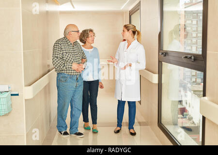 Coppia senior visite casa di cura e parla al medico o infermiere geriatrica Foto Stock