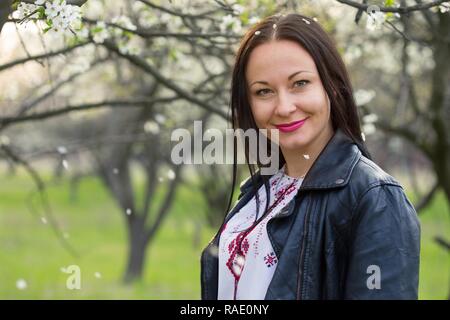 Bella ragazza in ricamo in un lussureggiante giardino. molla Foto Stock