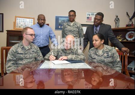 Col. Roman L. Hund, installazione commander, segni un African American Heritage mese annuncio nel suo ufficio 23 Gennaio, mentre il cap. Leo Barkardt, seduti da sinistra, seconda Lt. Jamecia Lazard, seduto a destra, Chris Roach, in piedi a sinistra, Senior Airman Noelle Valentine, centro permanente e Galen Williams, tutti i membri dell'African American Heritage mese consiglio, a guardare. Per tutto il mese di febbraio il Consiglio offrirà eventi per commemorare il ruolo significativo Americani africani hanno avuto negli Stati Uniti. Foto Stock