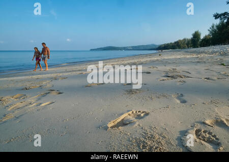 Un giovane su un inizio di mattina passeggiata a Bang Tao Beach, Phuket, Tailandia; in primo piano le impronte nella sabbia Foto Stock