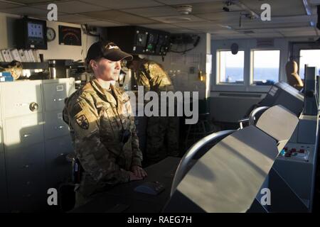 Chief Warrant Officer 2 Sarah Pietra, 2a combaciare con i mezzi di trasporto 411 distacco, scansiona l'orizzonte per navigare il supporto logistico Nave - 5 (LSV-5) "MG Charles P. lordo" nel Golfo Arabico, Gennaio 24, 2017. Foto Stock