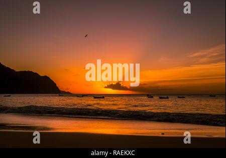 Tramonto sul piccolo e sperduto villaggio di Castara sulla bellissima isola di Tobago nei Caraibi con uccelli marini e ormeggiate barche da pesca. Paesaggio Foto Stock