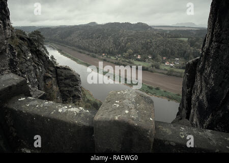 Deadpan dark Ponte Pietra Bastei nella Svizzera sassone con la nebbia di pioggia sul fiume Elba, parco nazionale Svizzera sassone. Foto Stock