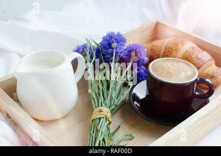 Romantico in estate la colazione a letto, vassoio con croissant freschi,  una tazza di caffè espresso con il latte e bouquet di cornflowers blu.  Buona mattina concetto. E Foto stock - Alamy