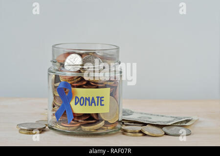 Soldi jar piena di monete con nastro blu e donare etichetta - Concetto di cancro della prostata carità e fondo di ricerca