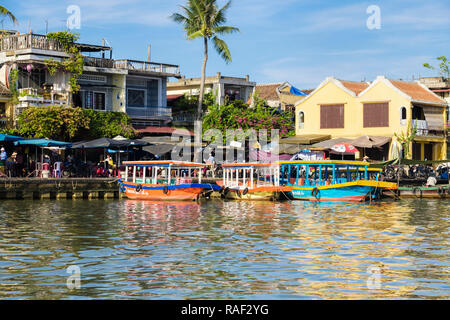 Vista su tutta l'acqua ai turisti tradizionali sampans per tour in barca ormeggiata lungo Thu Bon River nel quartiere vecchio della città storica. Hoi An Quang Nam Vietnam Foto Stock