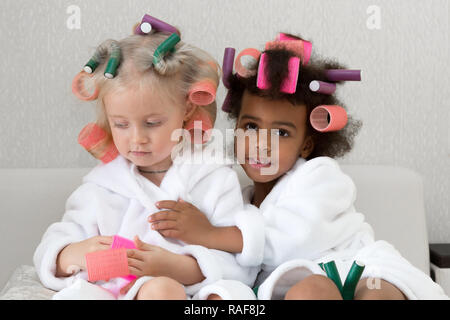 Bambine di diverse nazionalità in camici con dei bigodini. Foto Stock