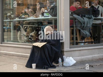 Senzatetto supplica individuale di fronte ad un ristorante nel quartiere di Chelsea di New York Martedì, Dicembre 25, 2018. (© Richard B. Levine) Foto Stock