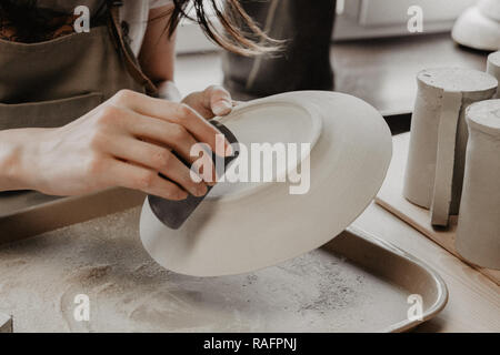 Donna fare ceramica. Vista dettagliata del processo di levigatura a piastra di argilla Foto Stock