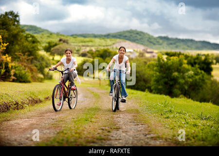 Due ragazze godendo la bicicletta sulla strada di ghiaia. Foto Stock