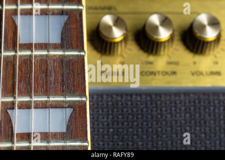 Chitarra e fret dettaglio marker, offuscata vecchio amplificatore manopole in background Foto Stock