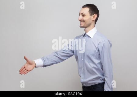 Profilo vista laterale ritratto di felice bello imprenditore di setole in luce classica maglietta blu in piedi, dando stretta di mano e saluto con sorriso toothy Foto Stock